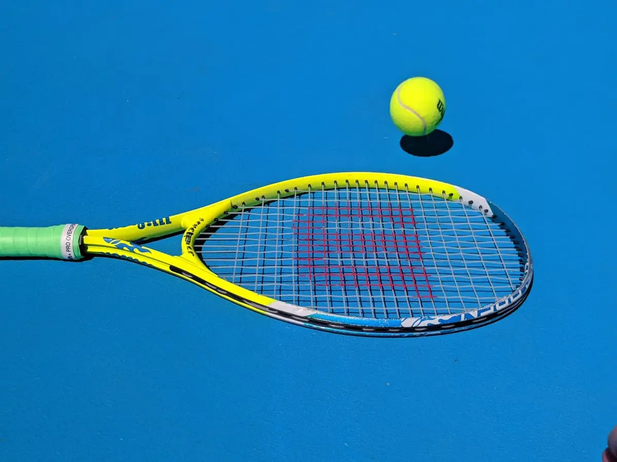 Teniszütő és labda kék háttér előtt